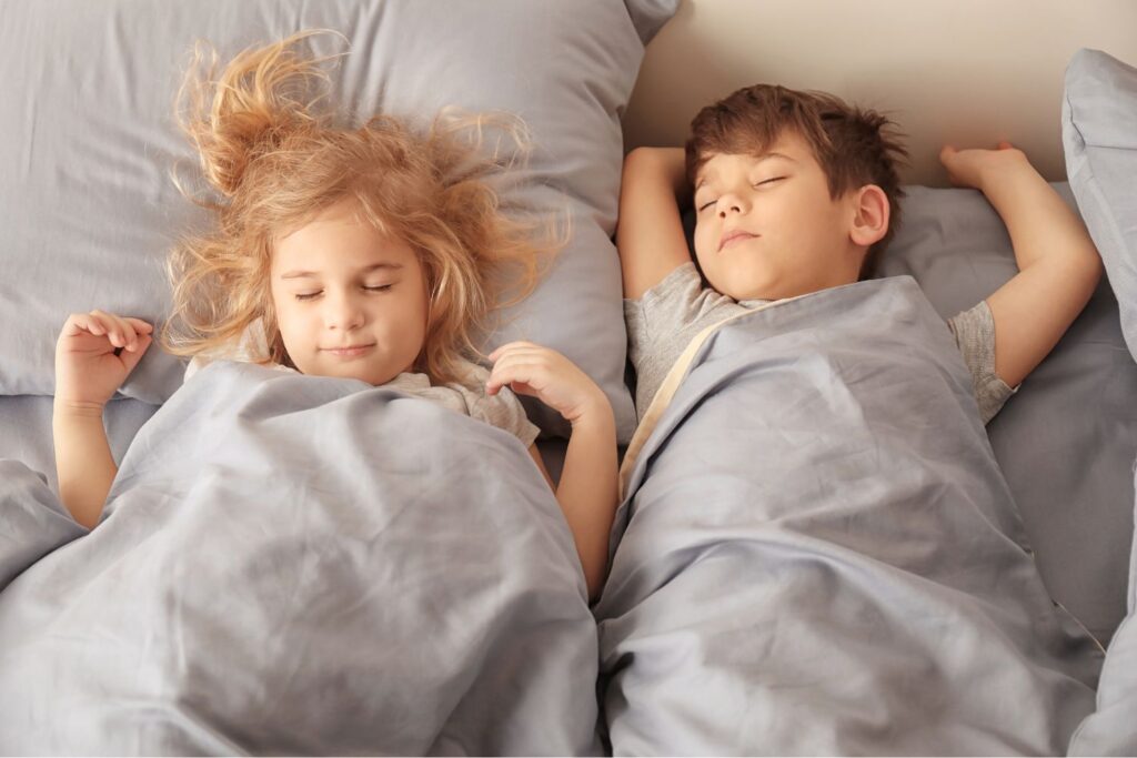 Zwei kinder schlafen friedlich in einem bett und wachen sanft auf.